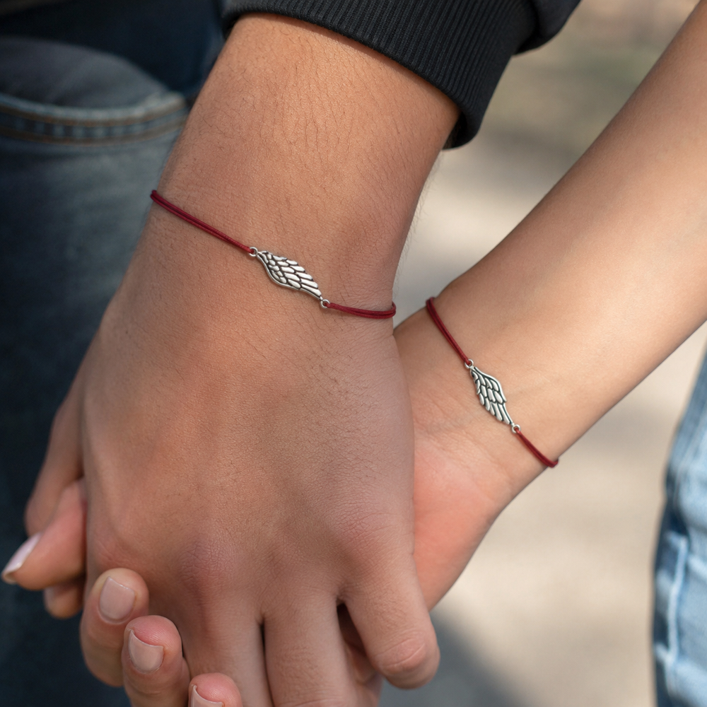 Couple holding hands outdoors wearing matching red string wing bracelets — Second Wing matching set