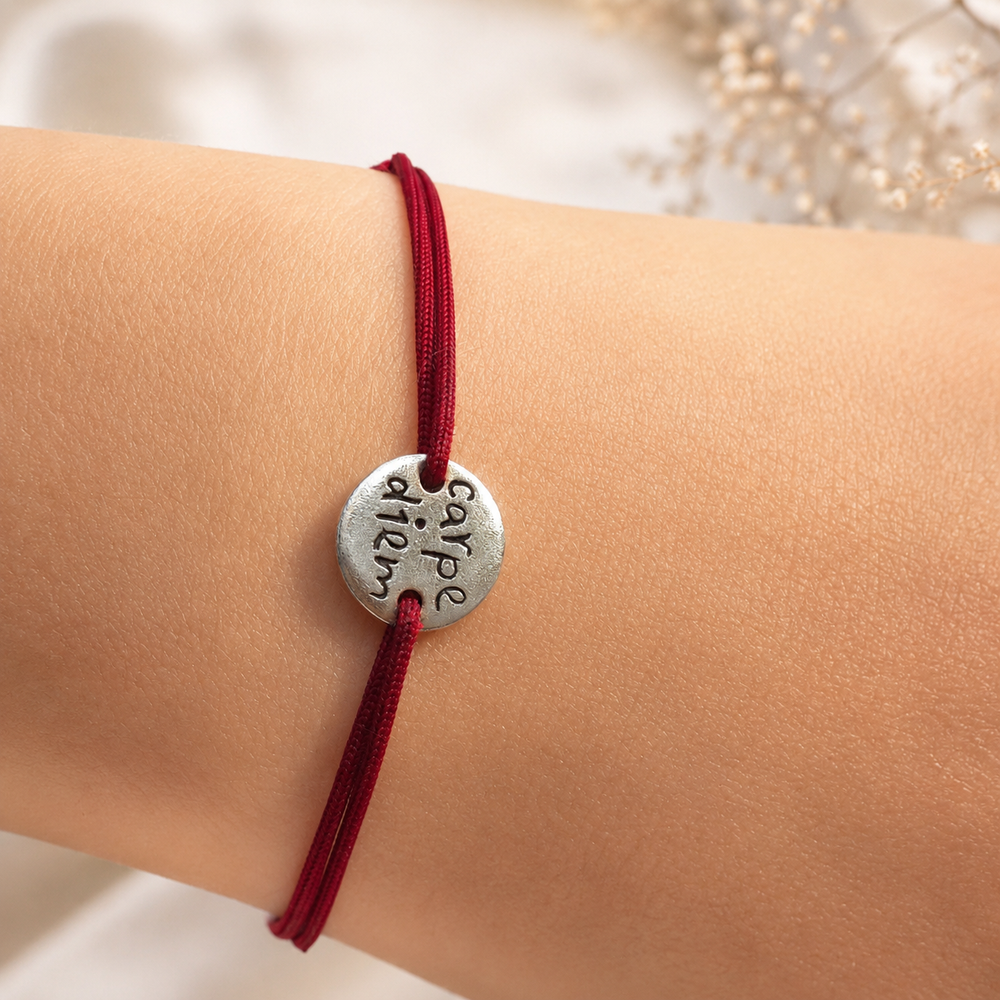 Carpe Diem Bracelet on a burgundy cord, worn among baby’s breath