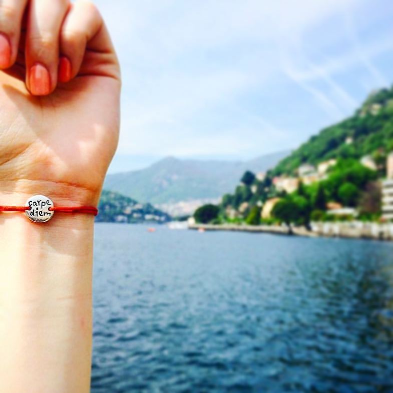 Carpe Diem Bracelet on a red cord, worn by the lake