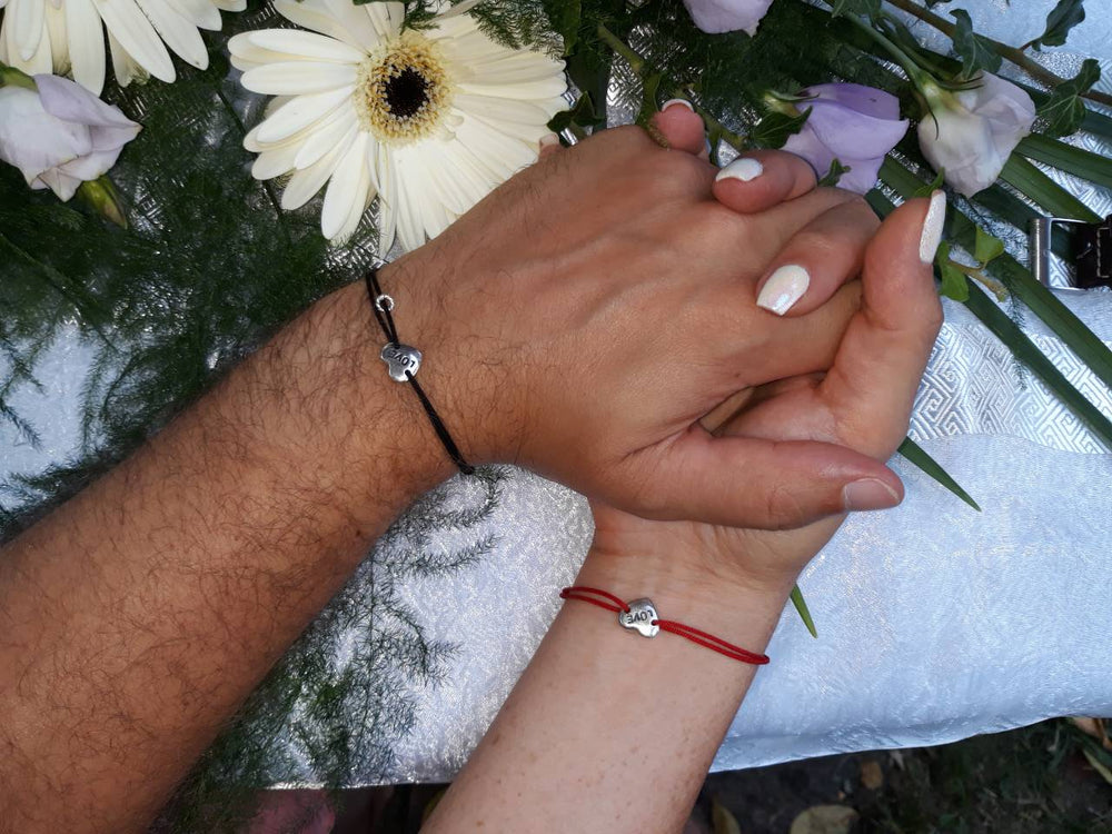 Two Love Bracelets on a couple’s intertwined hands — for those tied to each other